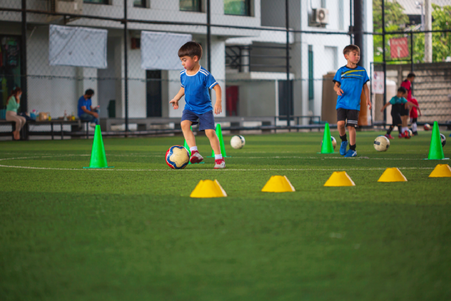 Young children learning basic ball control drills at our kids football training Seoni.